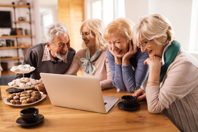 szczesliwa starsza kobieta i jej przyjaciele bawia sie podczas surfowania po internecie na komputerze w domu - Uniwersytet Trzeciego Wieku Online